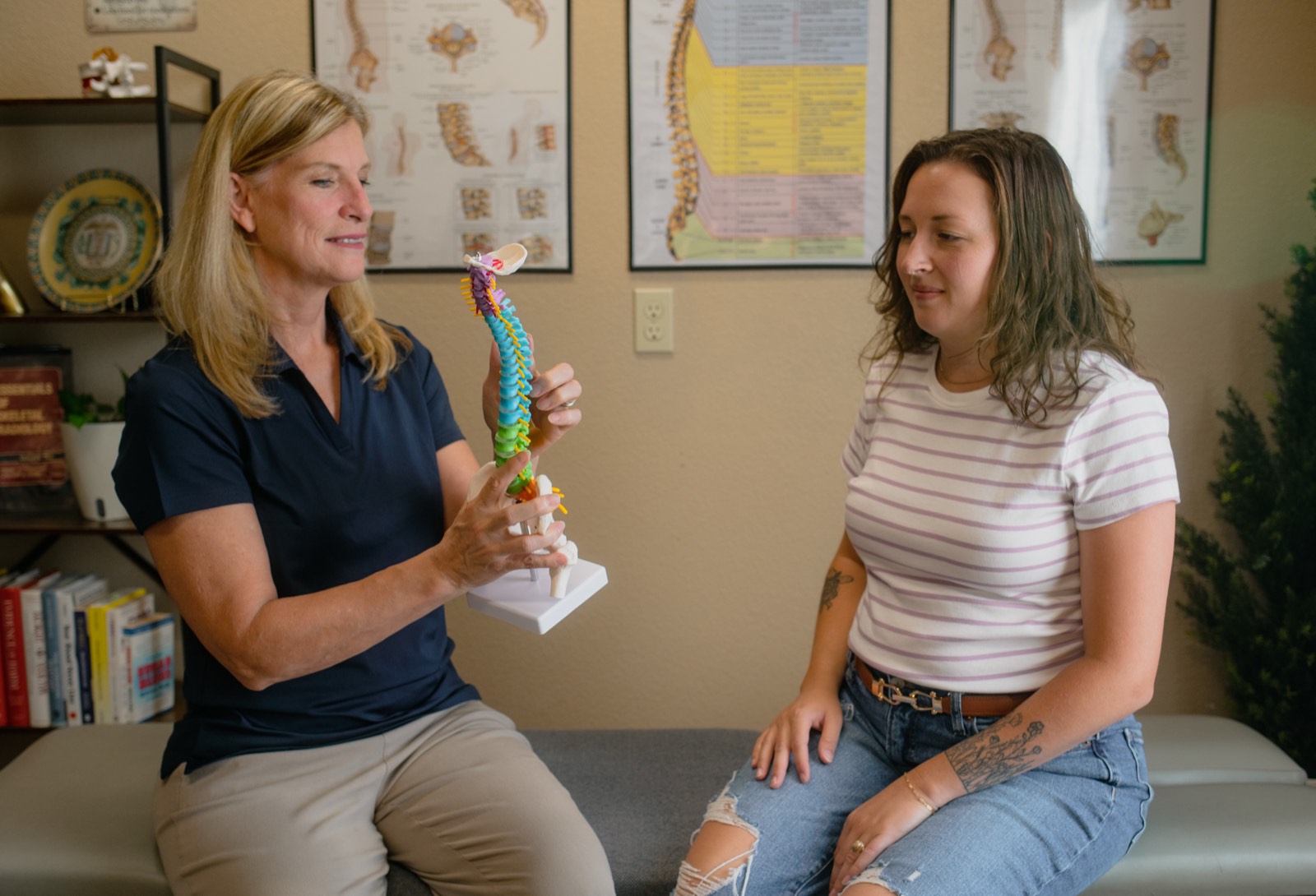 Dr. Emily using a spine model to explain care to a patient in the welcoming office.