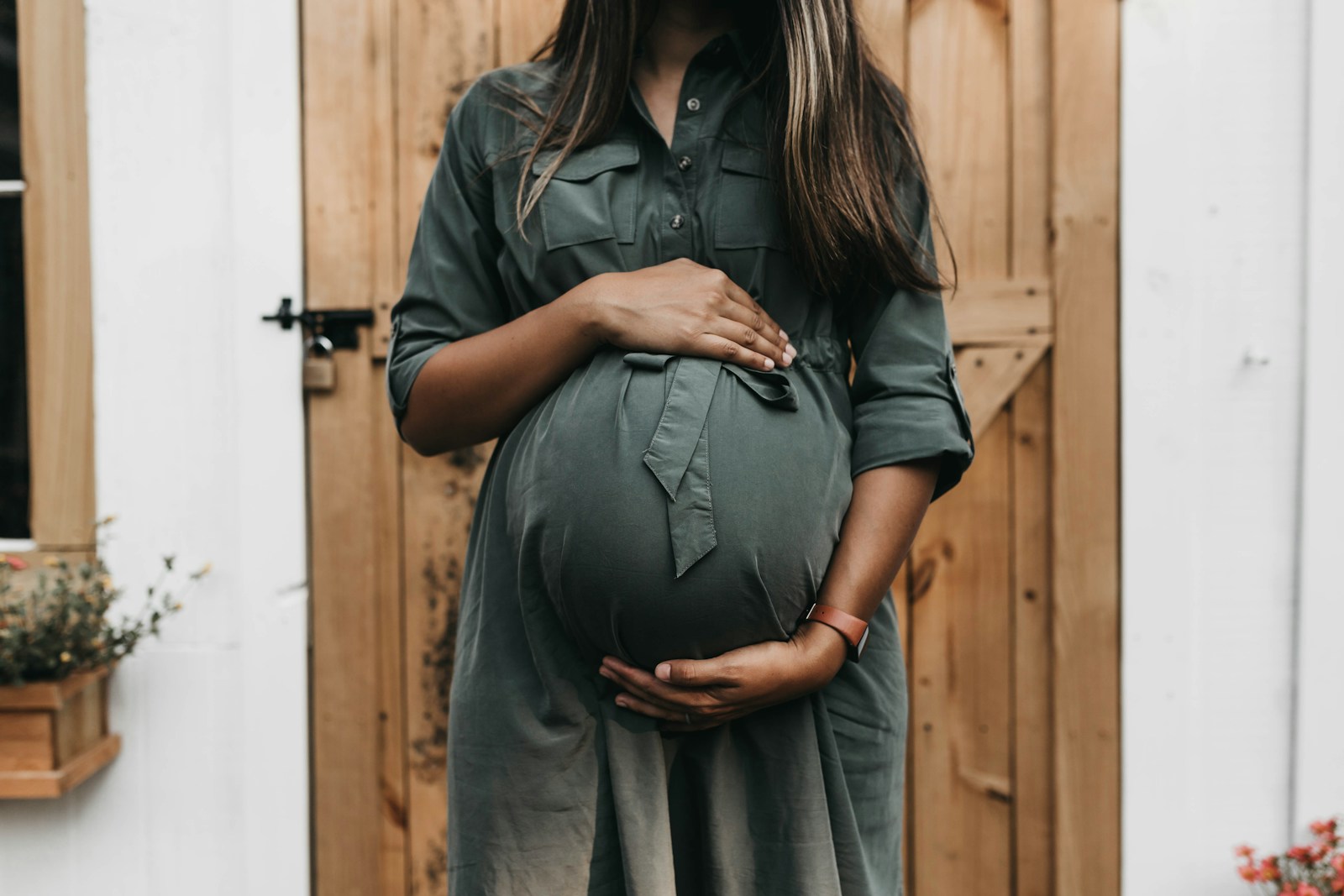 A pregnant woman gently cradling her belly.